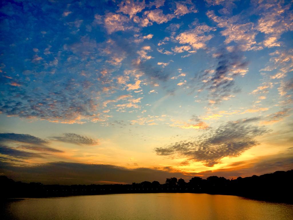 Sunset with water reflection and clouds scaterred across the sky